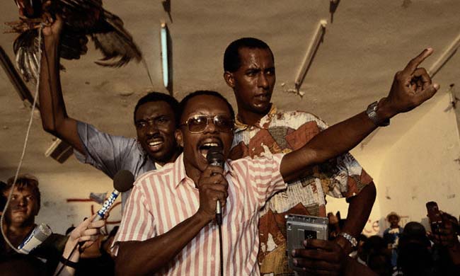 El candidato presidencial Jean-Bertrand Aristide da un discurso dos días antes de las elecciones presidenciales de Haití. Uno de sus seguidores sostiene un gallo. El símbolo de la campaña de Aristide.