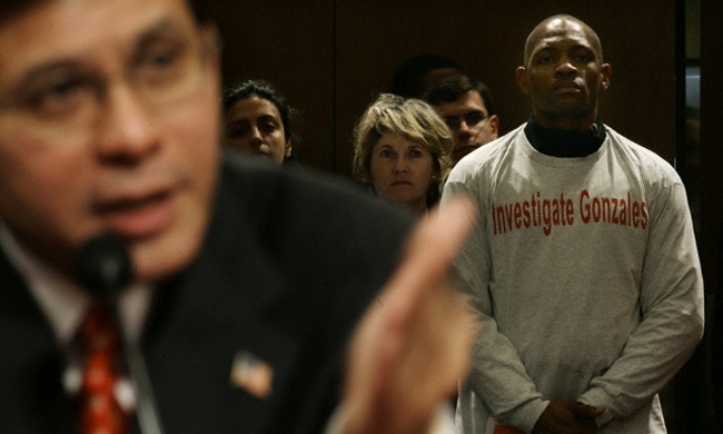 Anthony Chuck de Chicago, Illinois (a la derecha), y representante del grupo "Veteranos contra la tortura" viste una camisa que dice "Investiguen a Gonzales", mientras el candidato a Fiscal General de los Estados Unidos (a la izquierda) testifica en su audiencia de confirmación en Washington el 6 de enero del 2005. Gonzales, cuyas controversiales opiniones legales como consejero de la Casa Blanca han causado un fiero debate, fue elegido por el presidente George Bush para reemplazar al Fiscal General John Ashcroft.