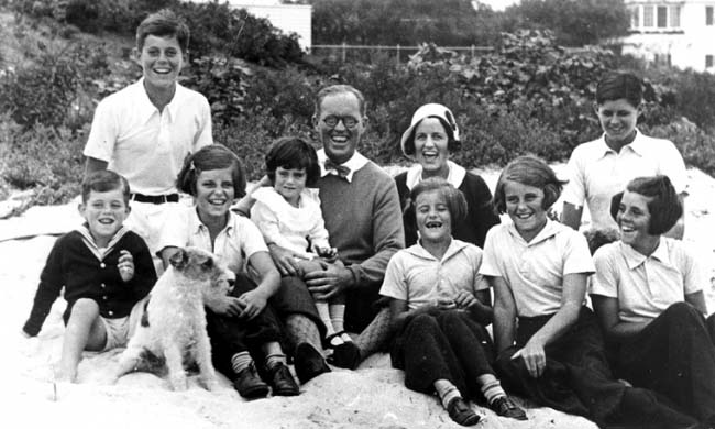 La família Kennedy en Hyannis Port el 4 de septiembre de 1931. De izquierda a derecha: Robert Kennedy, John F. Kennedy, Eunice Kennedy, Jean Kennedy (en las piernas de) Joseph P. Kennedy Sr., Rose Fitzgerald Kennedy (detrás de) Patricia Kennedy, Kathleen Kennedy, Joseph P. Kennedy Jr. (detrás de) Rosemary Kennedy. Edward Kennedy todavía no había nacido. El perro se llamaba &quot;Buddy&quot;.